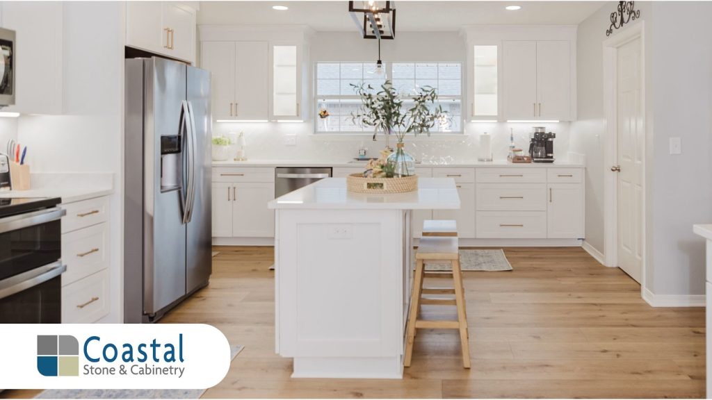 Coastal Stone and Cabinetry modern white kitchen remodel featuring quartz countertops a central island white cabinets and luxury vinyl plank flooring in Fairhope Alabama. Photo by Cindy McCrory.